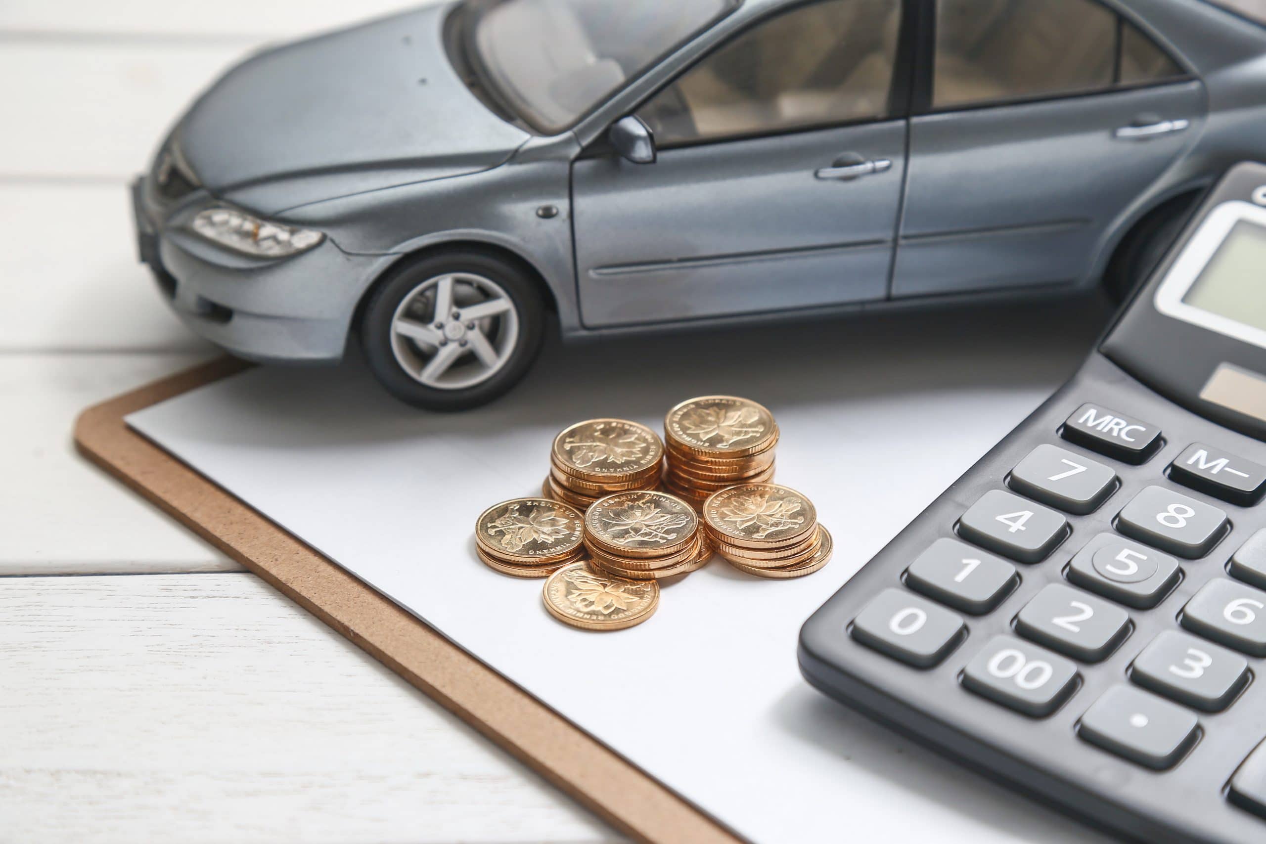 car model,calculator and coins on white table