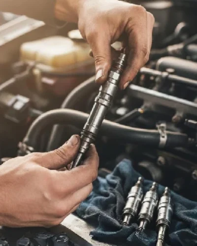 Inspección técnica de inyectores defectuosos por un profesional: manos de un mecánico revisando un inyector de combustible en el motor para documentar un vicio oculto.